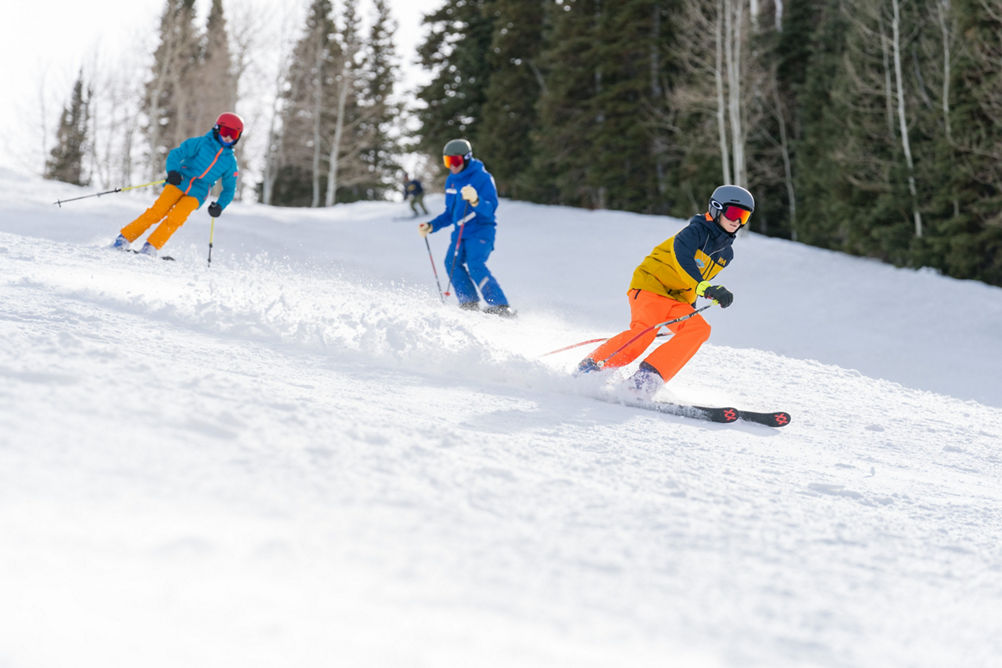 Older children skiing with an instructor (ATP)