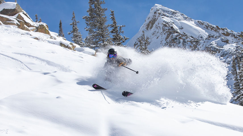 Female skier making turn in fresh snow with Mount Crested Butte in the background