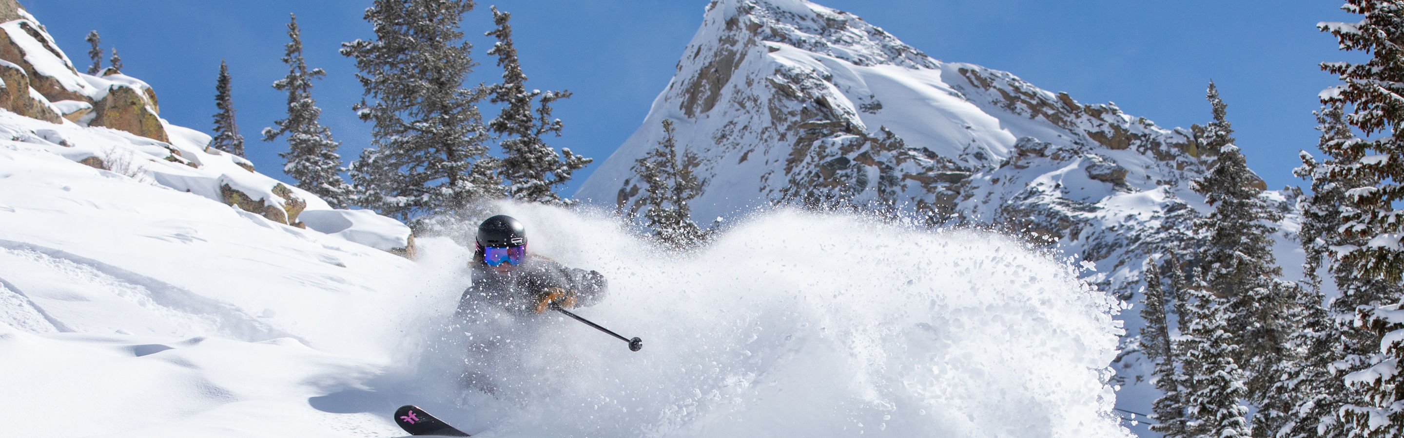 Female skier making turn in fresh snow with Mount Crested Butte in the background