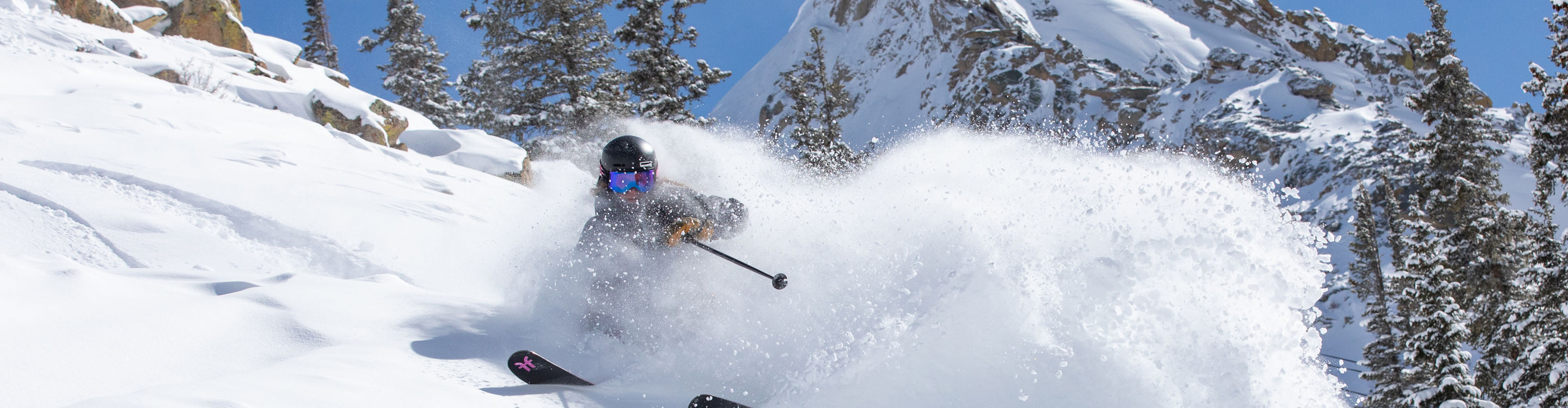 Female skier making turn in fresh snow with Mount Crested Butte in the background