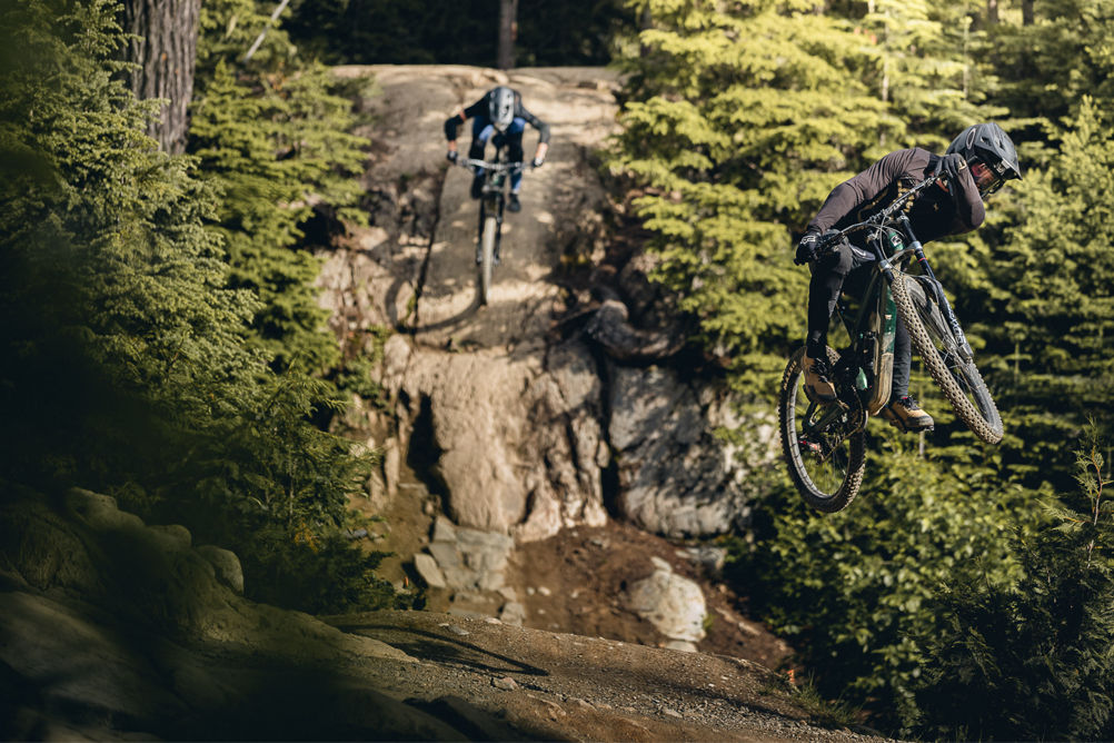 Two Mountain Bikers hitting features simultaneously 