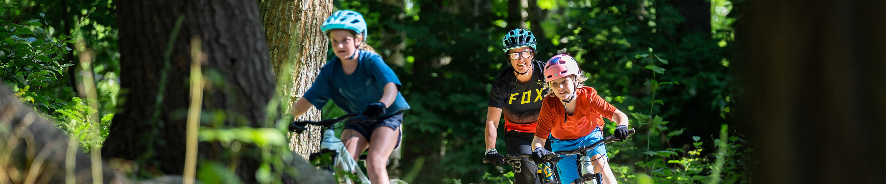 Family Riding on Mountain Biking Trail Through Trees at Mount Sunapee