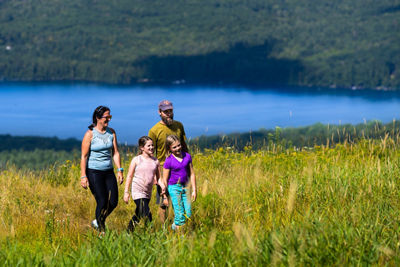 Family Hiking Through Tall Grass with Lake Sunapee in the Background