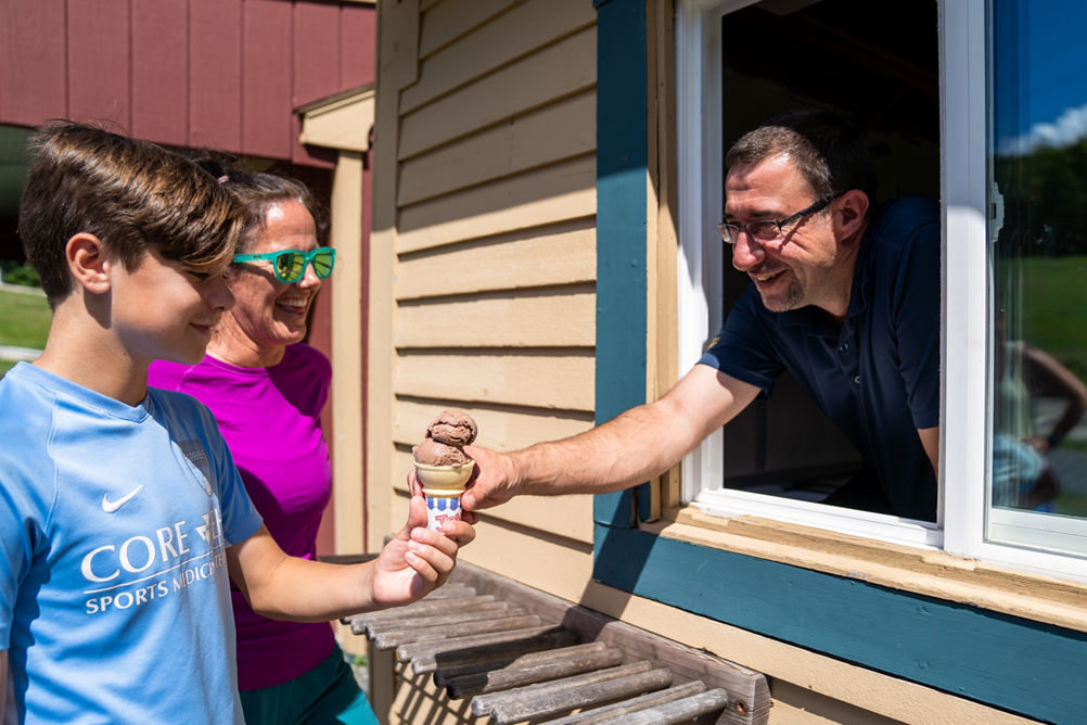 Man Hands a Young Boy a Chocolate Ice Cream Cone at Mount Sunapee