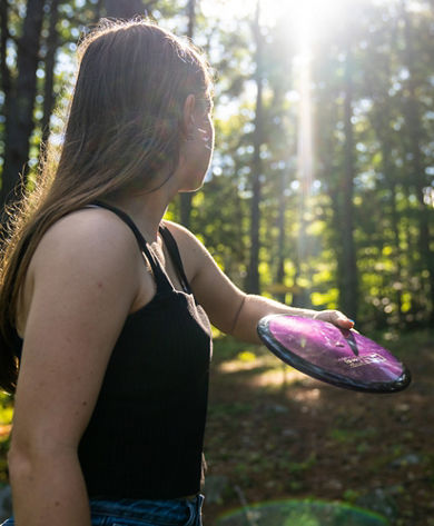 Woman Prepares to Throw Disc Through Trees at Mount Sunapee