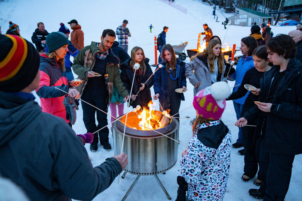 Guests Gather Around Campfire to Roast Marshmallows at New Year's Eve Celebration at Mount Sunapee