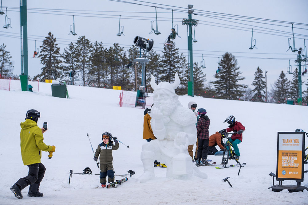 Kid Takes Photo with Snow Sculpture at Ullr Fest at Afton Alps