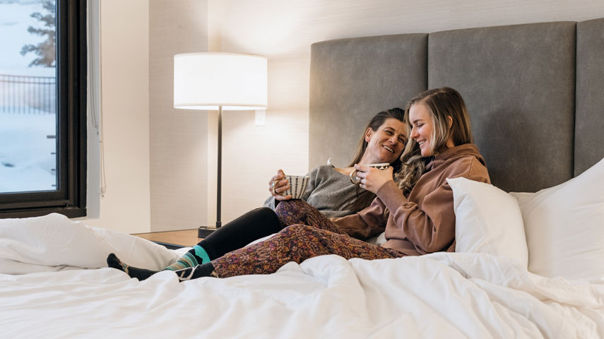Couple Enjoys Sipping Coffee Together in Bed in Their Unit at Lift Lodging at Park City