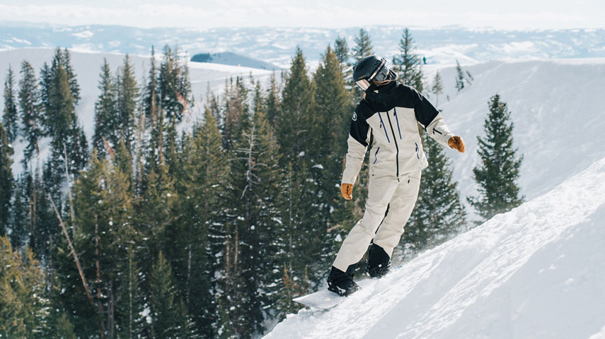 Snowboarder in Black and White Jacket Stands on Steep Edge of Advanced Terrain at Park City
