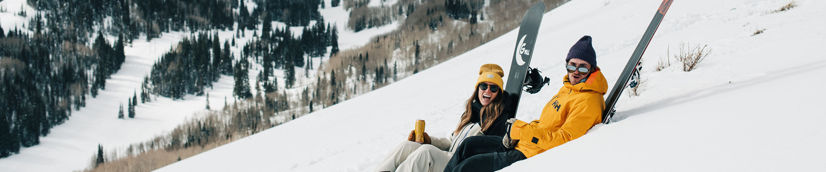 Skier and Snowboarder Relax Against Their Equipment at Park City with Scenic Background View
