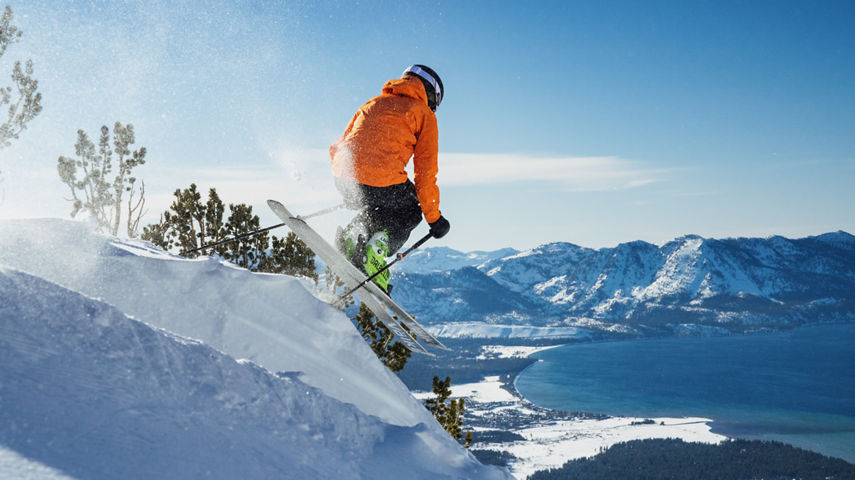 Skier Leaps Off Advanced Terrain Ledge at Heavenly with Scenic View of Lake Tahoe in the Background