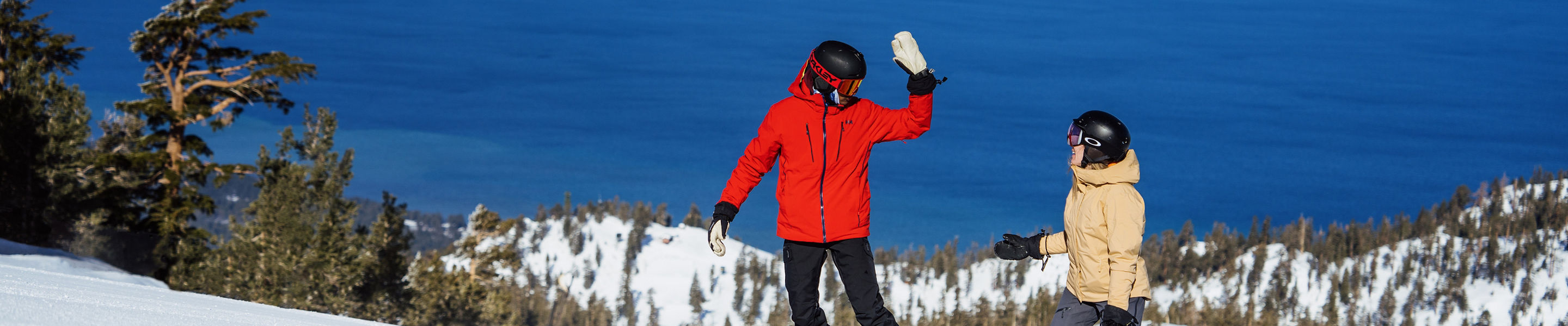 Snowboarders Prepare to High Five at the Top of a Run at Heavenly with a Scenic View of Lake Tahoe in the Background