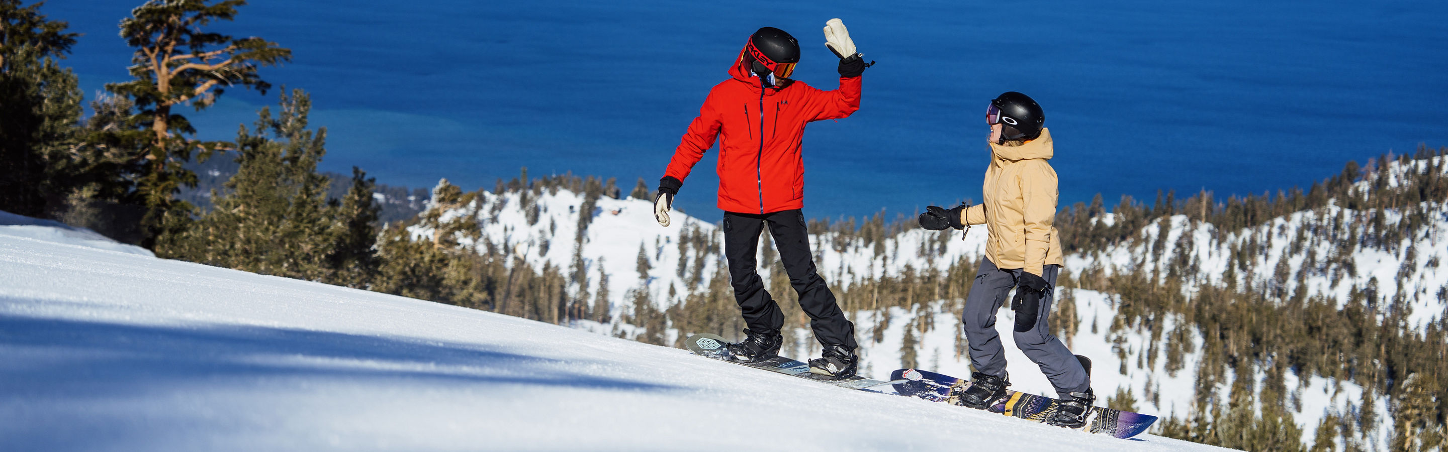 Snowboarders Prepare to High Five at the Top of a Run at Heavenly with a Scenic View of Lake Tahoe in the Background