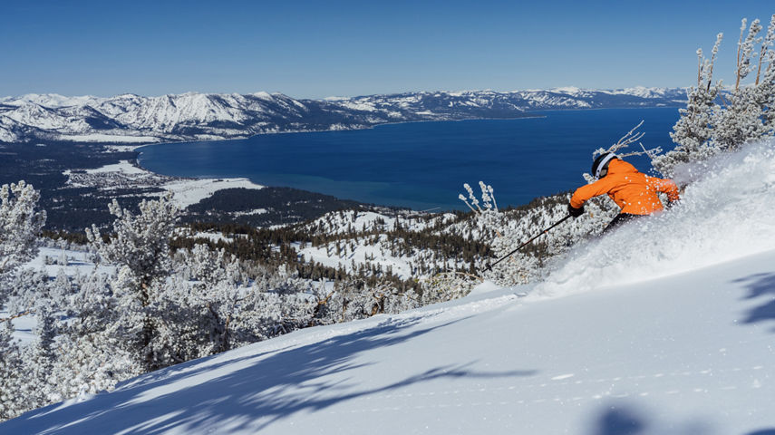 Skier Shreds Through Fresh Powder on a Bluebird Day at Heavenly with Lake Tahoe in the Background