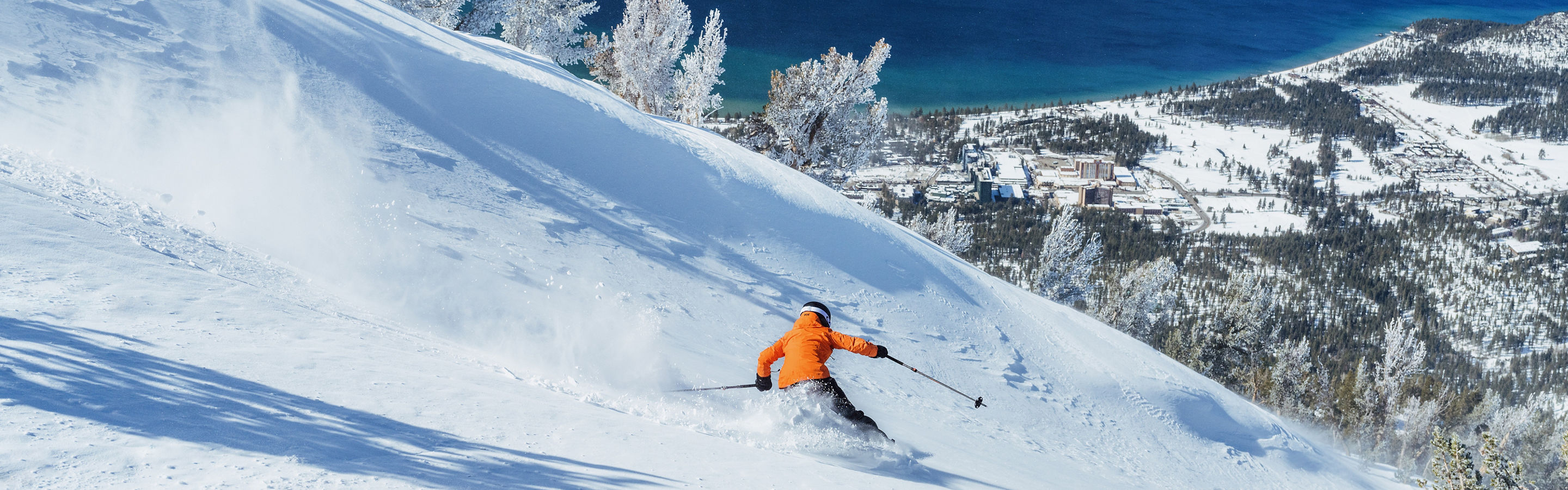Skier Shreds Through Fresh Powder on a Bluebird Day at Heavenly with Lake Tahoe in the Background