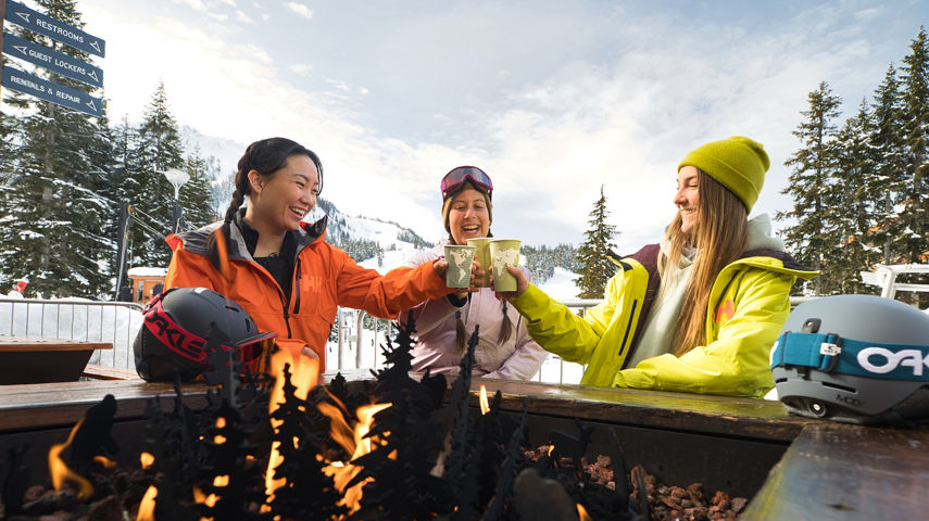 Resort Guests Drink Coffee Around a Firepit at Stevens Pass Base Area