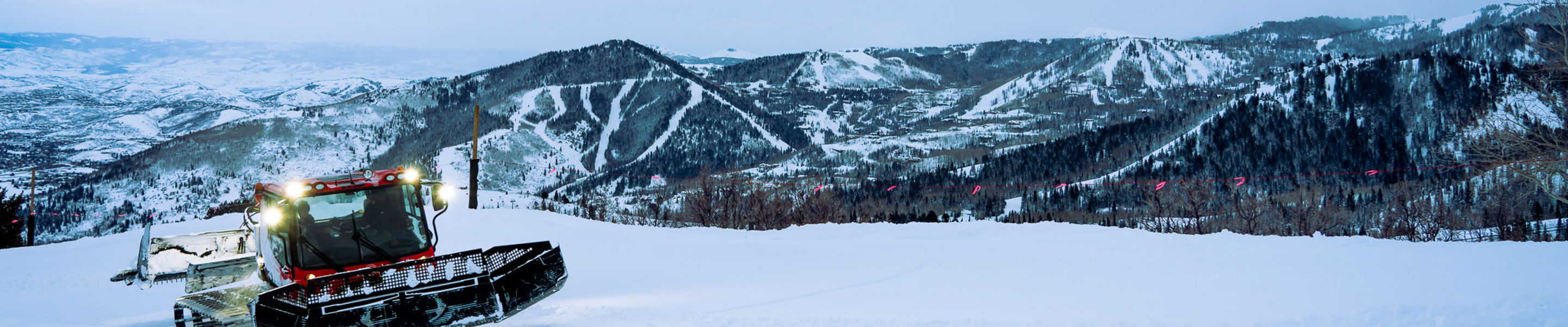 Snowcat coming up Apex Ridge with ski runs in the background