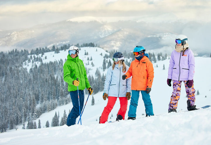 Skier and Snowboarders Chat at the Top of a Run with a Scenic Background at Keystone