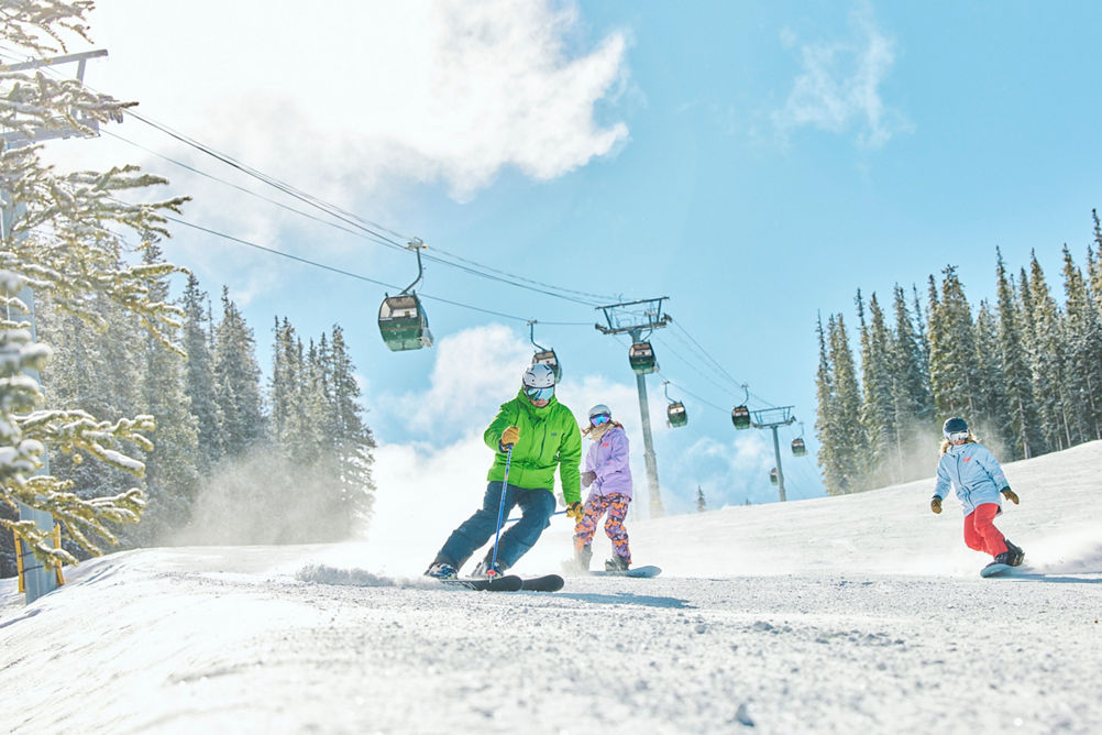 Group of Snowboarders and a Skier Enjoying Riding Down Fresh Snow on a Trail at Keystone