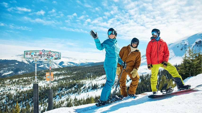Skier and Snowboarders Stand at the Top of Mustang Trail at Breckenridge with Scenic Background