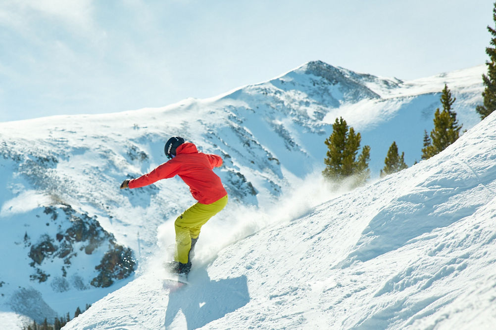 Snowboarder in Red Jacket Rides Down Advanced Terrain Through Trees at Breckenridge