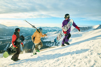 Skier and Snowboarders Hike Up Trail with Scenic Background at Breckenridge
