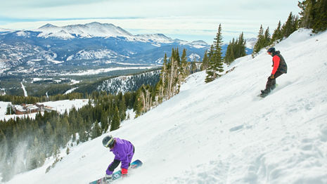 Snowboarders Ride Down Advanced Terrain with Scenic Background at Breckenridge