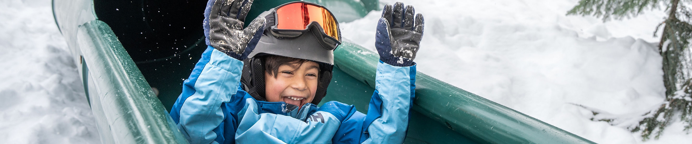 Young Child Wearing Ski Gear Slides Down Green Tube Slide at Whistler Blackcomb