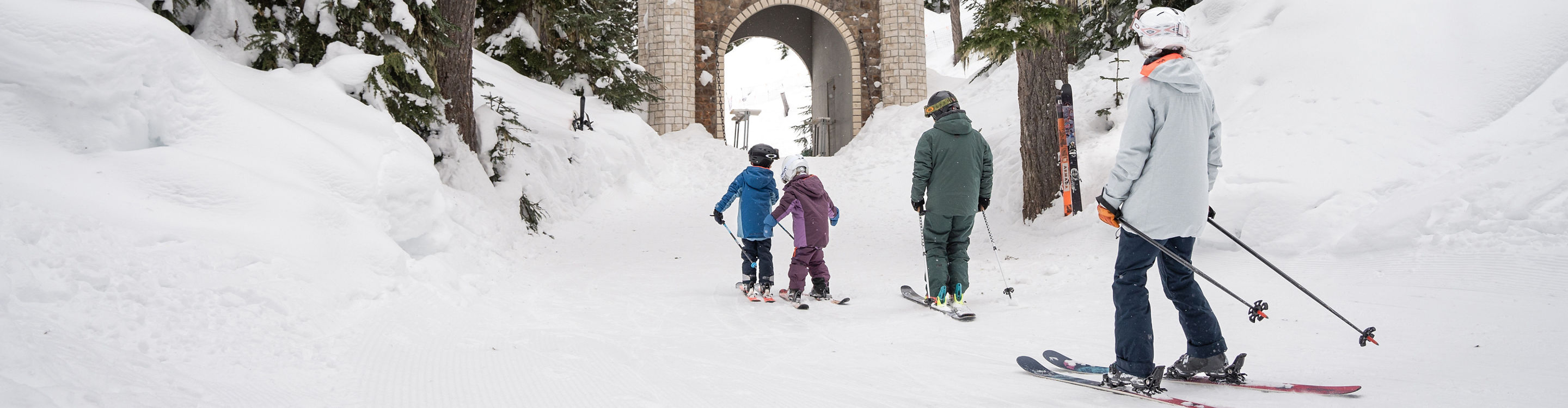 Family Skis Through Easy Trail Toward a Bridge Underpass at Whistler Blackcomb