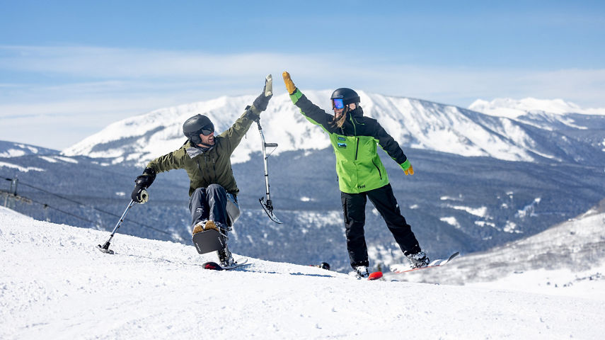 Adaptive Skier and Instructor High Five while Skiing at Crested Butte