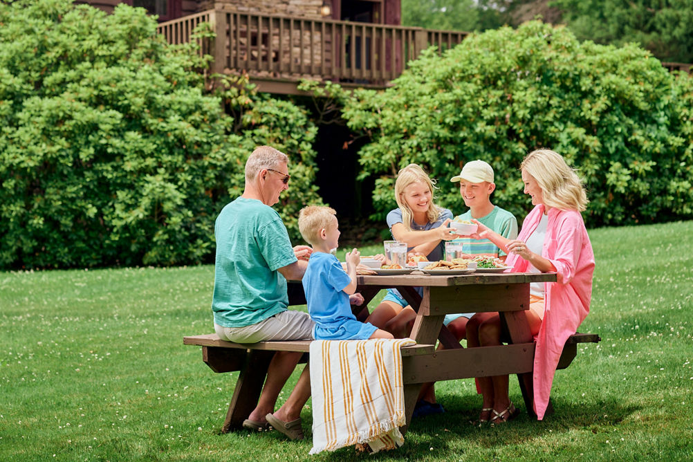Family Enjoying a Picnic Lunch on a Summer Day While Staying at Birch Chalet at Seven Springs