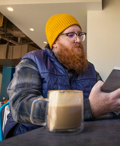 Man Sips Coffee while Reading a Book at Northstar Vous