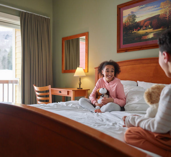 Siblings Snuggle Stuffies in Bed at Okemo