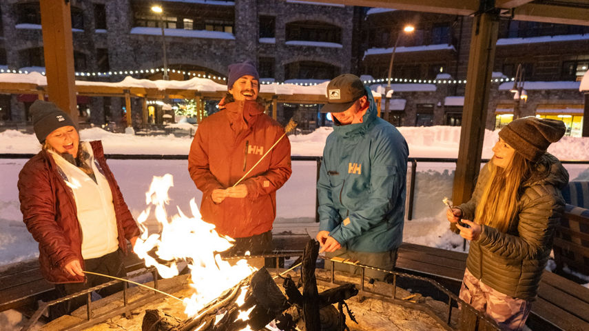 Group of Friends Stand Around Campfire and Make S'mores at Northstar