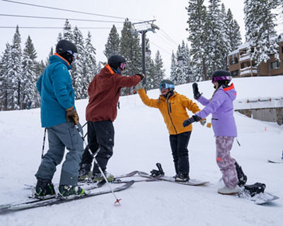 Friends Celebrate and High Five After Ski and Snowboard Run at Northstar
