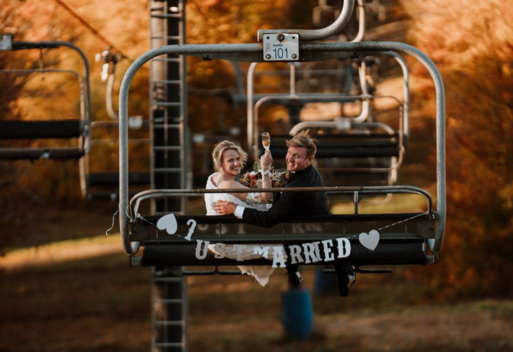 Bride and Groom Riding Chairlift Among Fall Foliage at Mount Sunapee