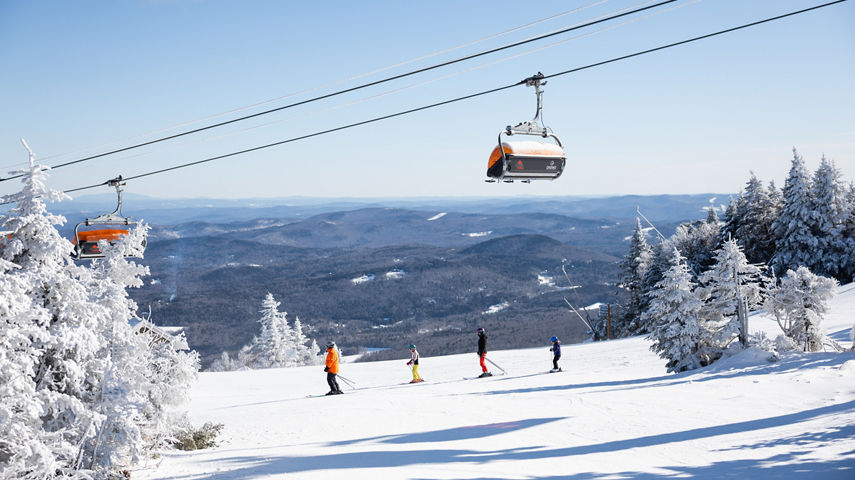 Family Skis Down Trail Beneath Iconic Orange Bubble Chairlifts at Okemo