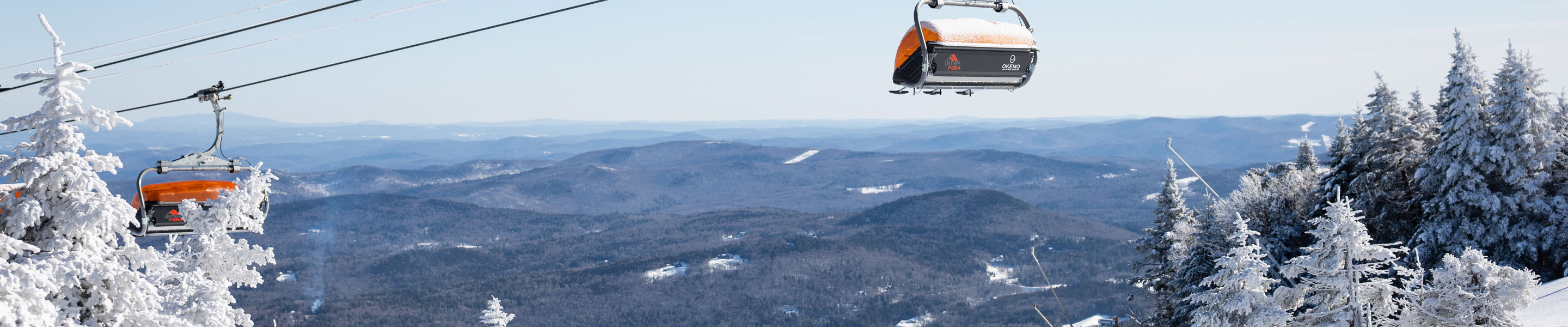 Family Skis Down Trail Beneath Iconic Orange Bubble Chairlifts at Okemo