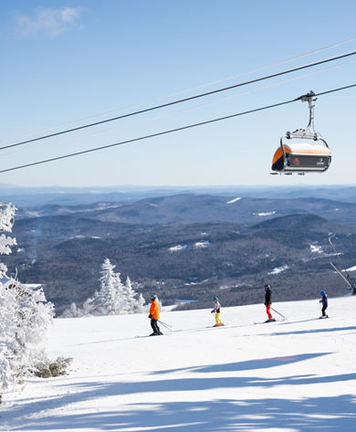 Family Skis Down Trail Beneath Iconic Orange Bubble Chairlifts at Okemo