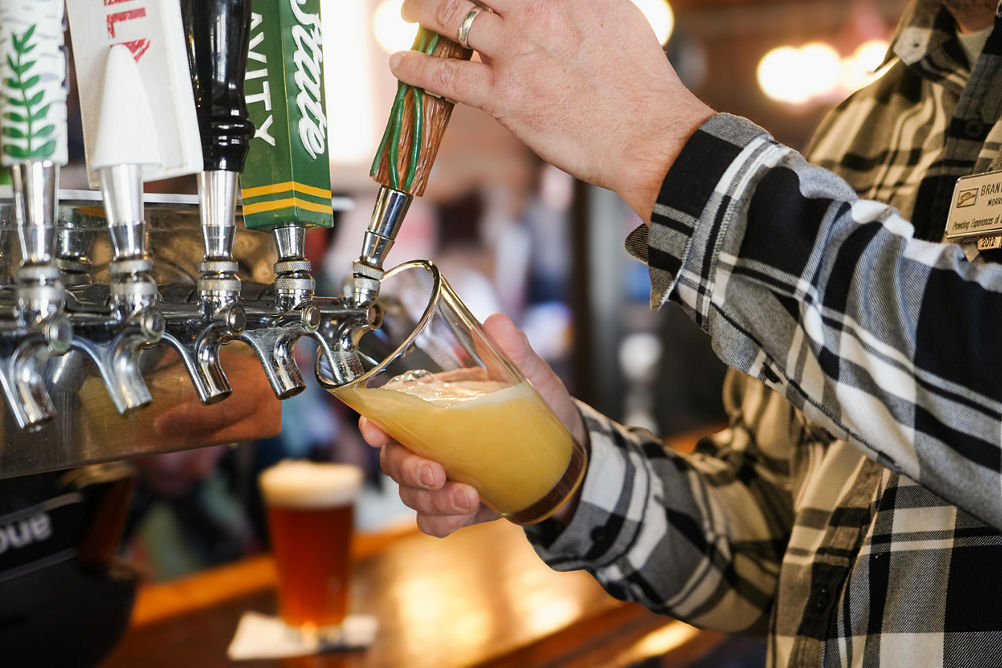 Man Pouring a Beer from Tap at The Den