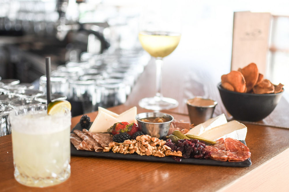 Meat and Cheese Board with a Glass of Wine a Cocktail and Chips at Umbrella Bar