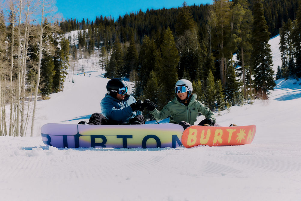 Couple Sit to Take a Break and Fist-Bumps with Snowboards