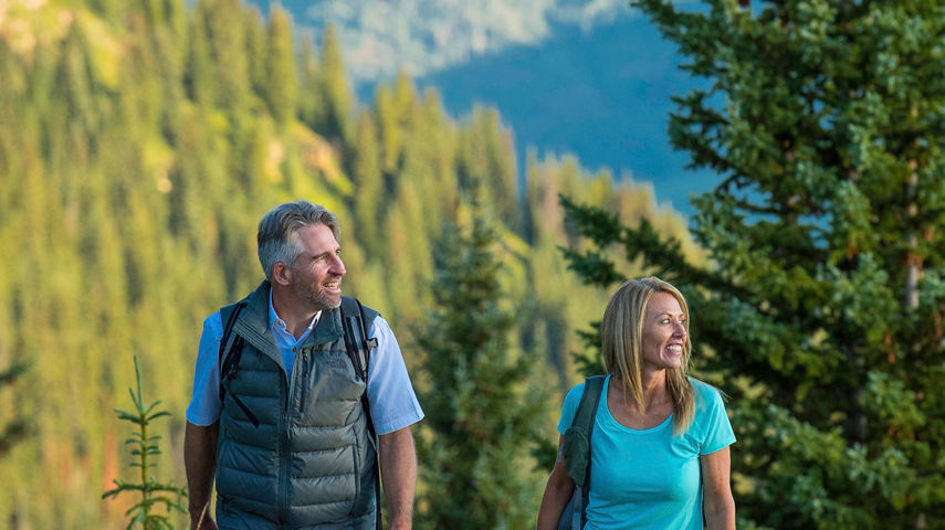 Couple hikes through wildflowers in Vail, CO.