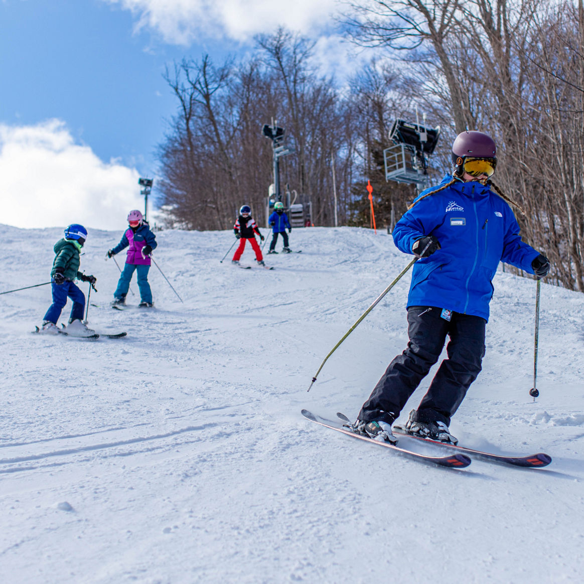 Children ski behind instructor 