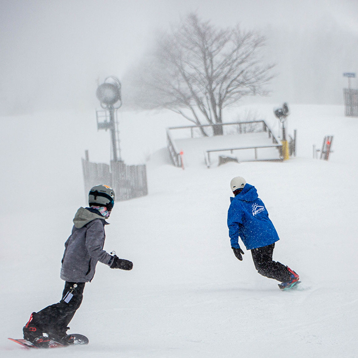 Child Snowboards behind instructor