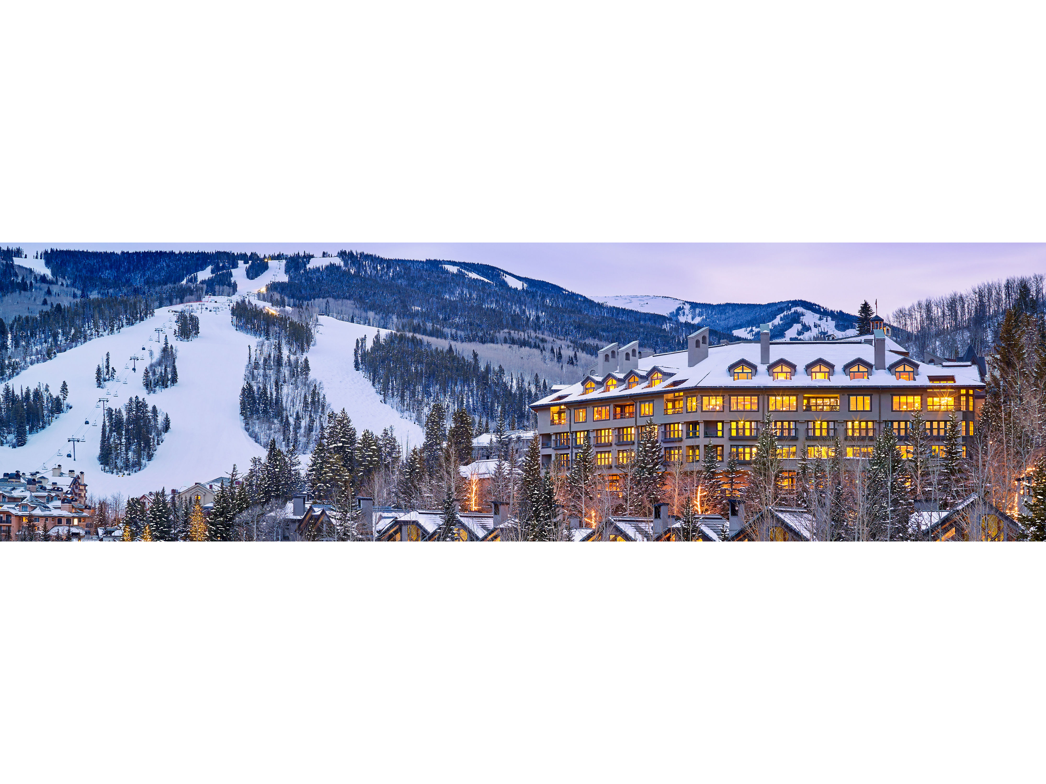 The Pines glowing at dusk next to a snow covered Crested Butte mountain. 
