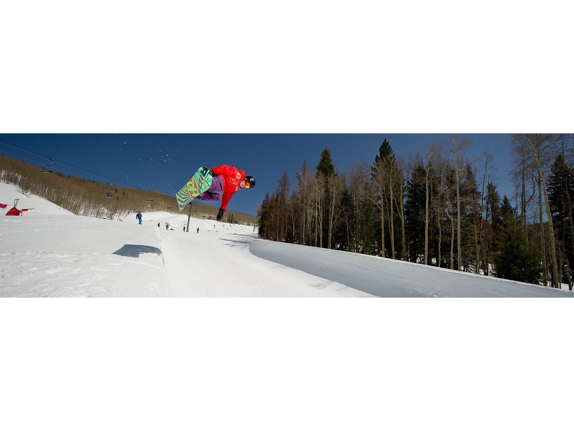 Snowboarder wearing a helmet rides a half pipe in the terrain park in Vail, Colorado