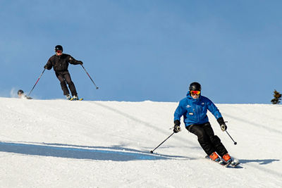 two skiers cresting a hill